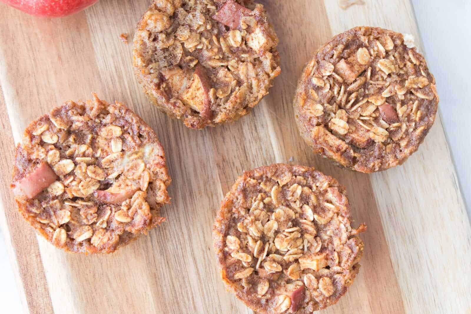 Homemade apple cinnamon oatmeal muffins on a wooden cutting board, healthy breakfast idea.