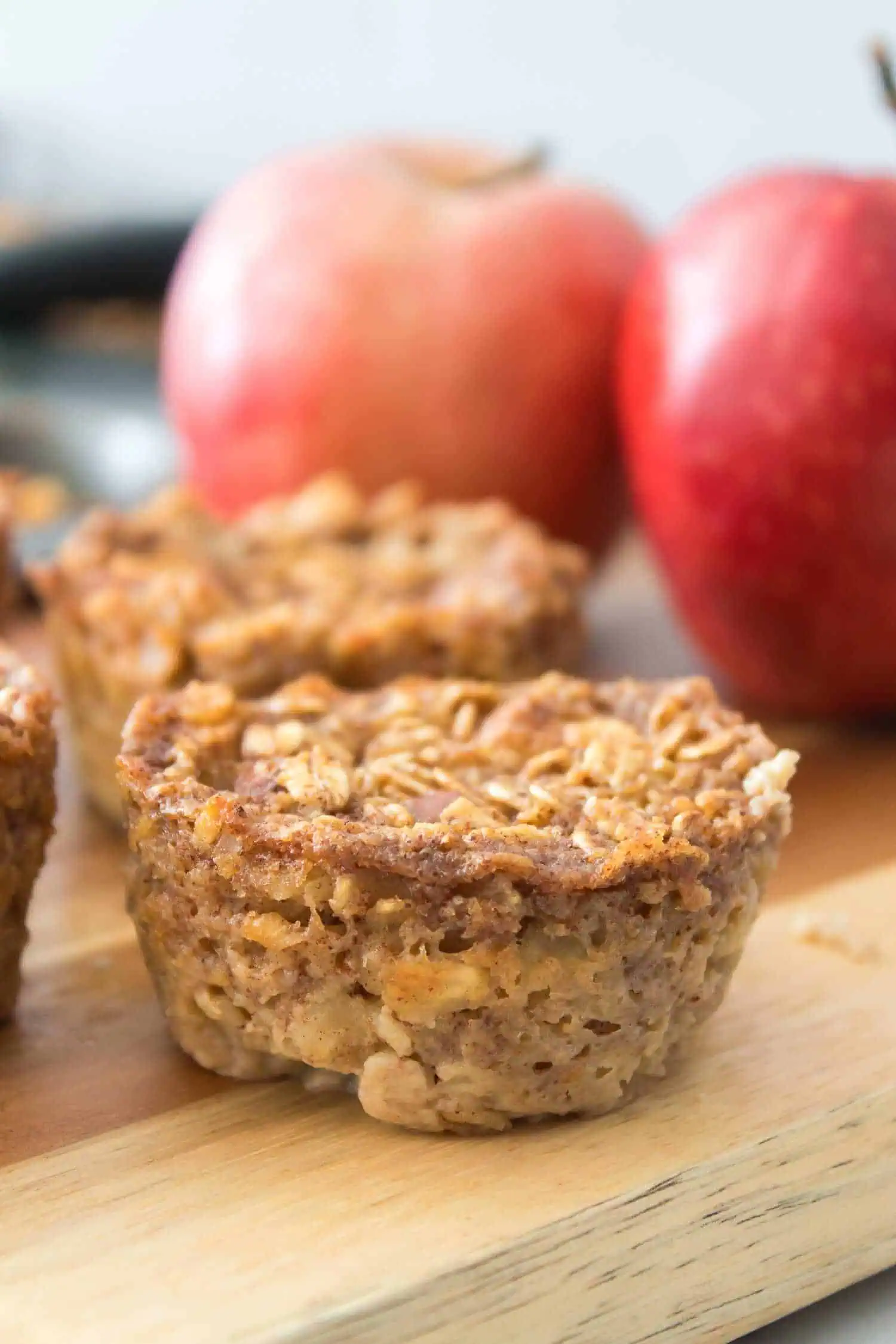 Homemade apple cinnamon oatmeal muffins on a wooden cutting board.
