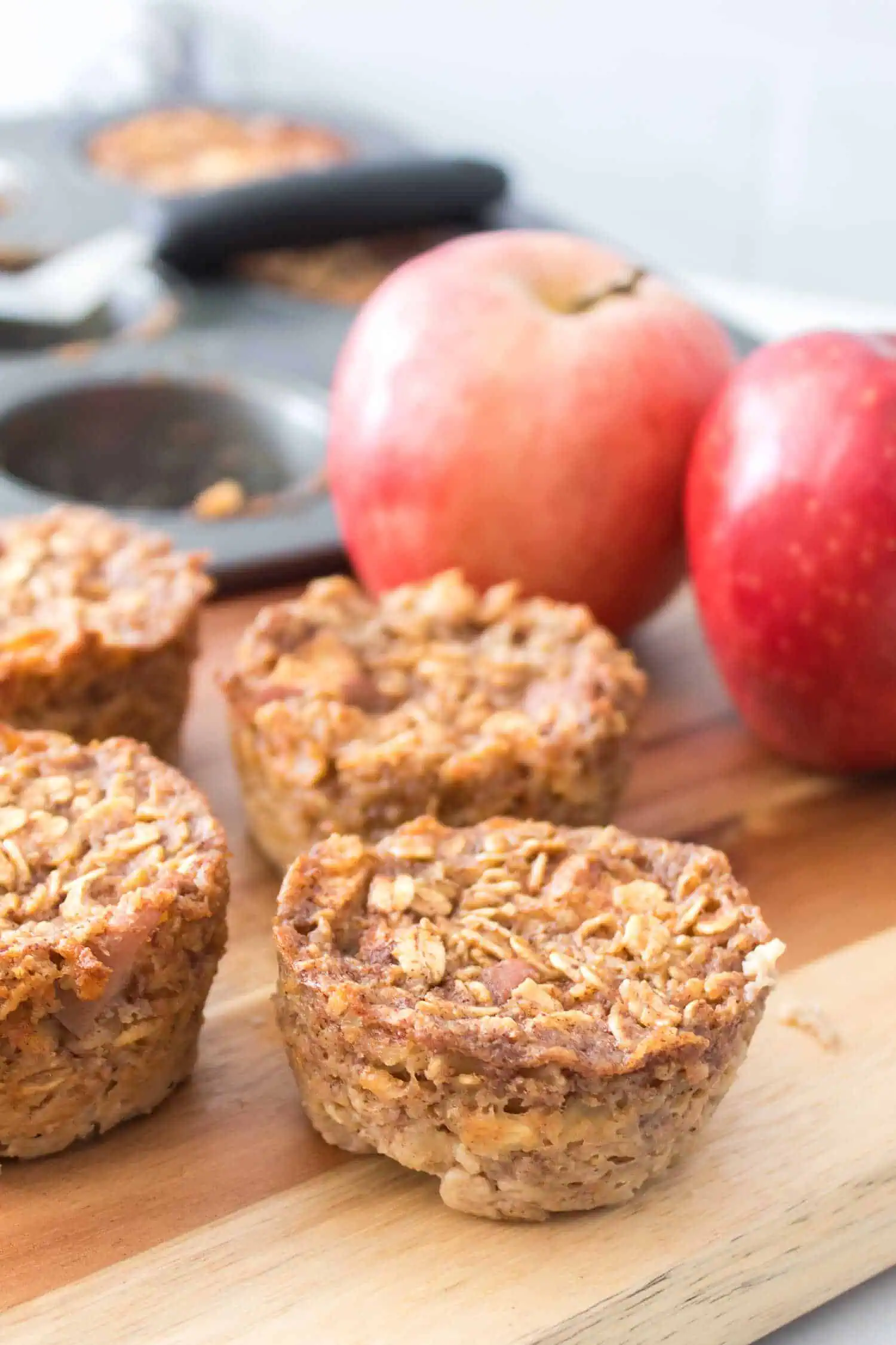 Oatmeal apple muffins with fresh apples in the background, healthy baked good for breakfast or snack.