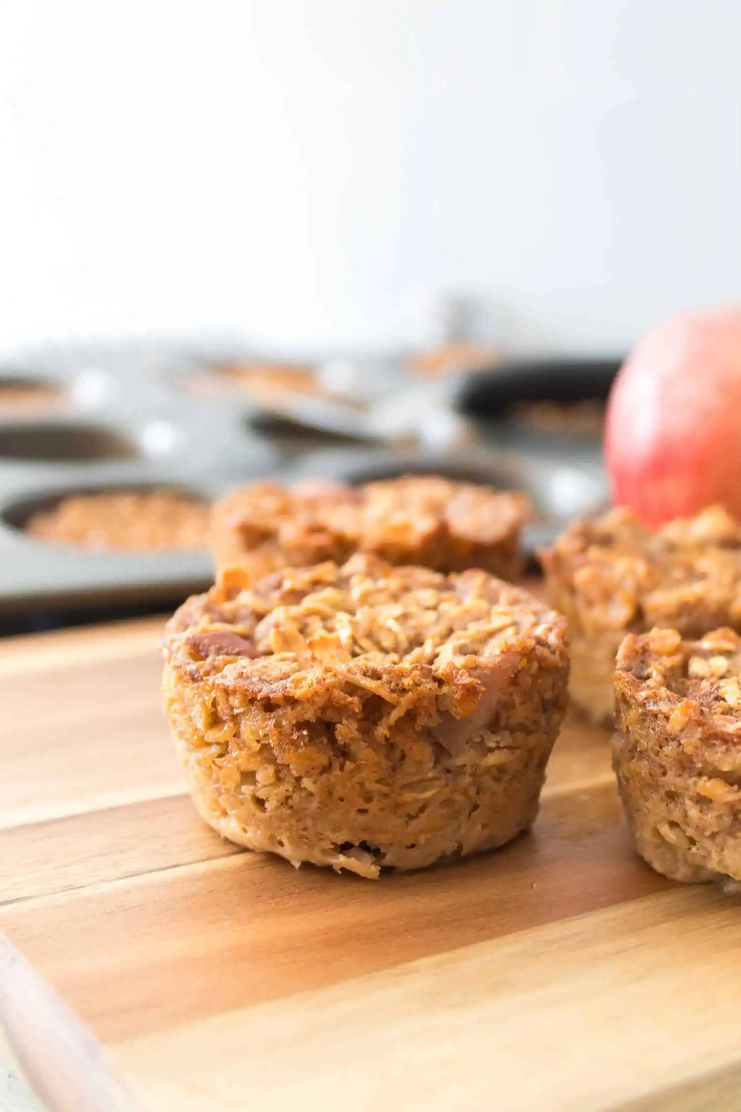 Vegan apple cinnamon muffins on wooden cutting board, healthy baked goods for breakfast or snack.