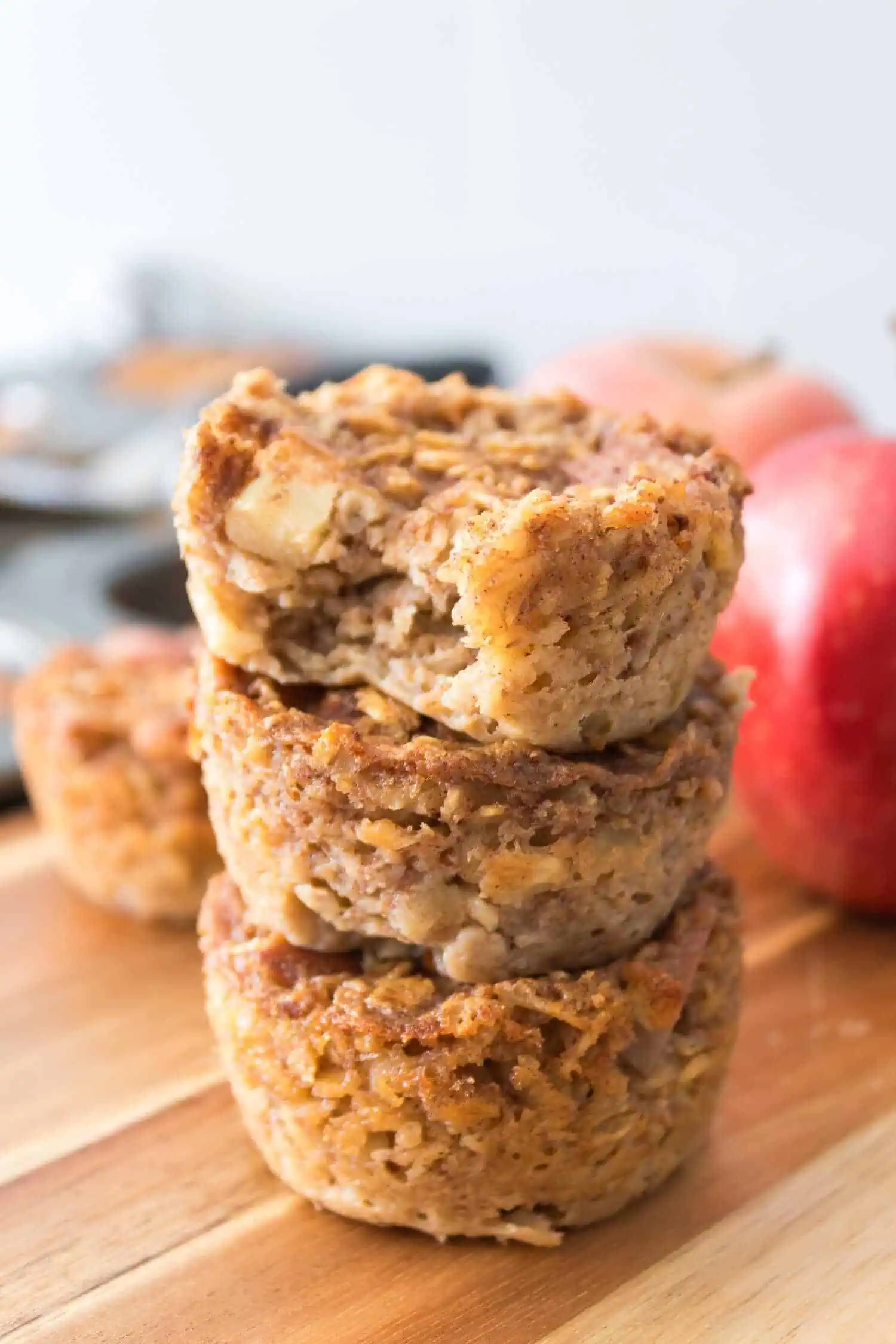 Delicious oatmeal apple muffins stacked on a wooden surface for healthy baking inspiration.