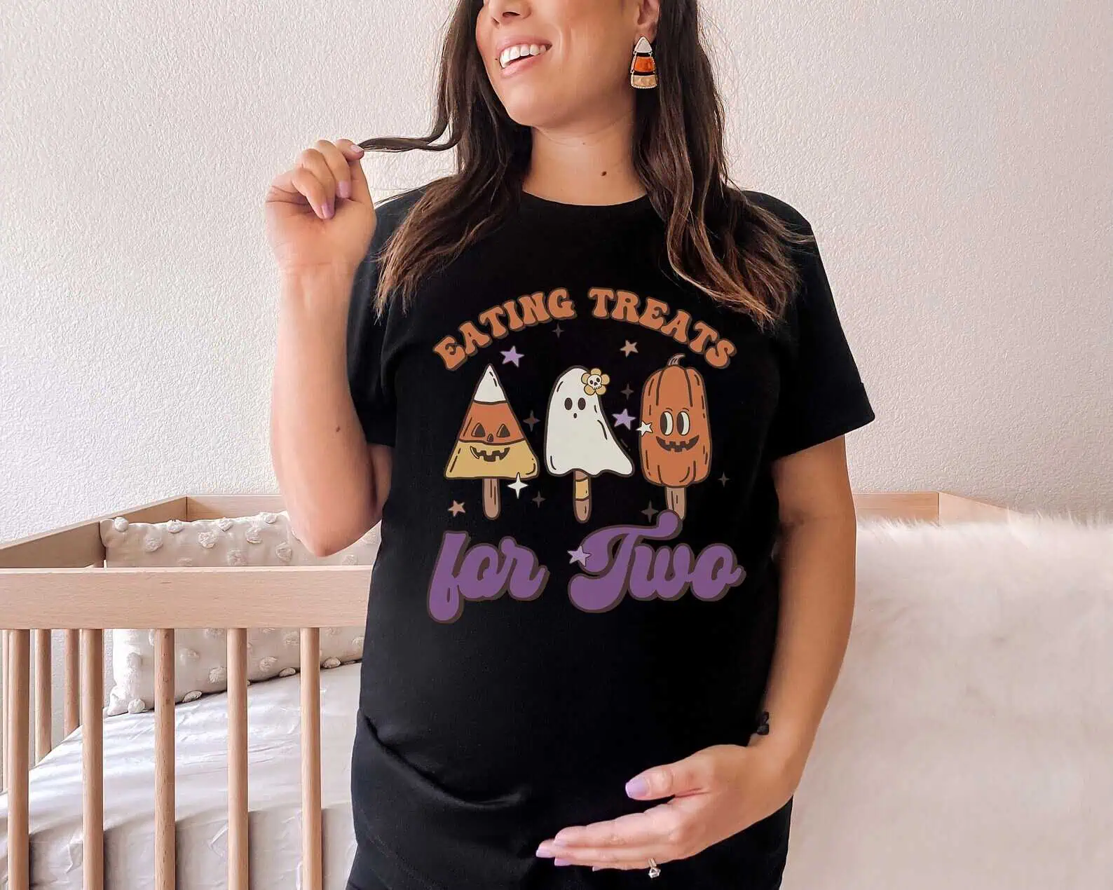 Comfortable pregnant woman wearing a Halloween-themed "Eating Treats for Two" t-shirt, celebrating surrogacy and family building.