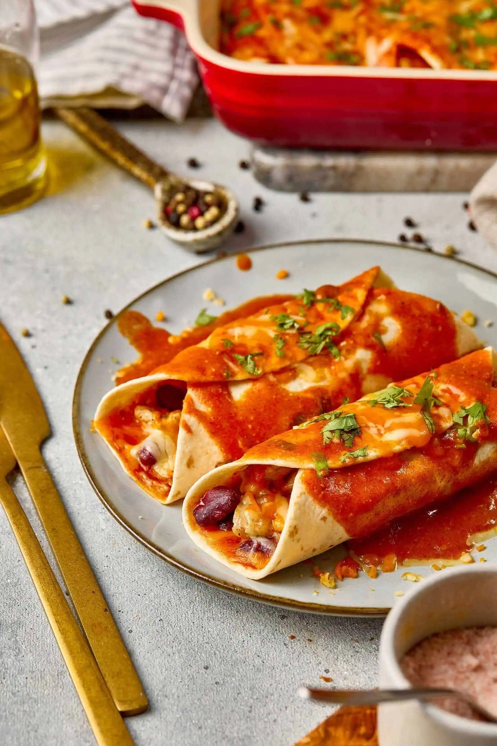 Delicious beef burritos with cheese and fresh herbs on a white plate.