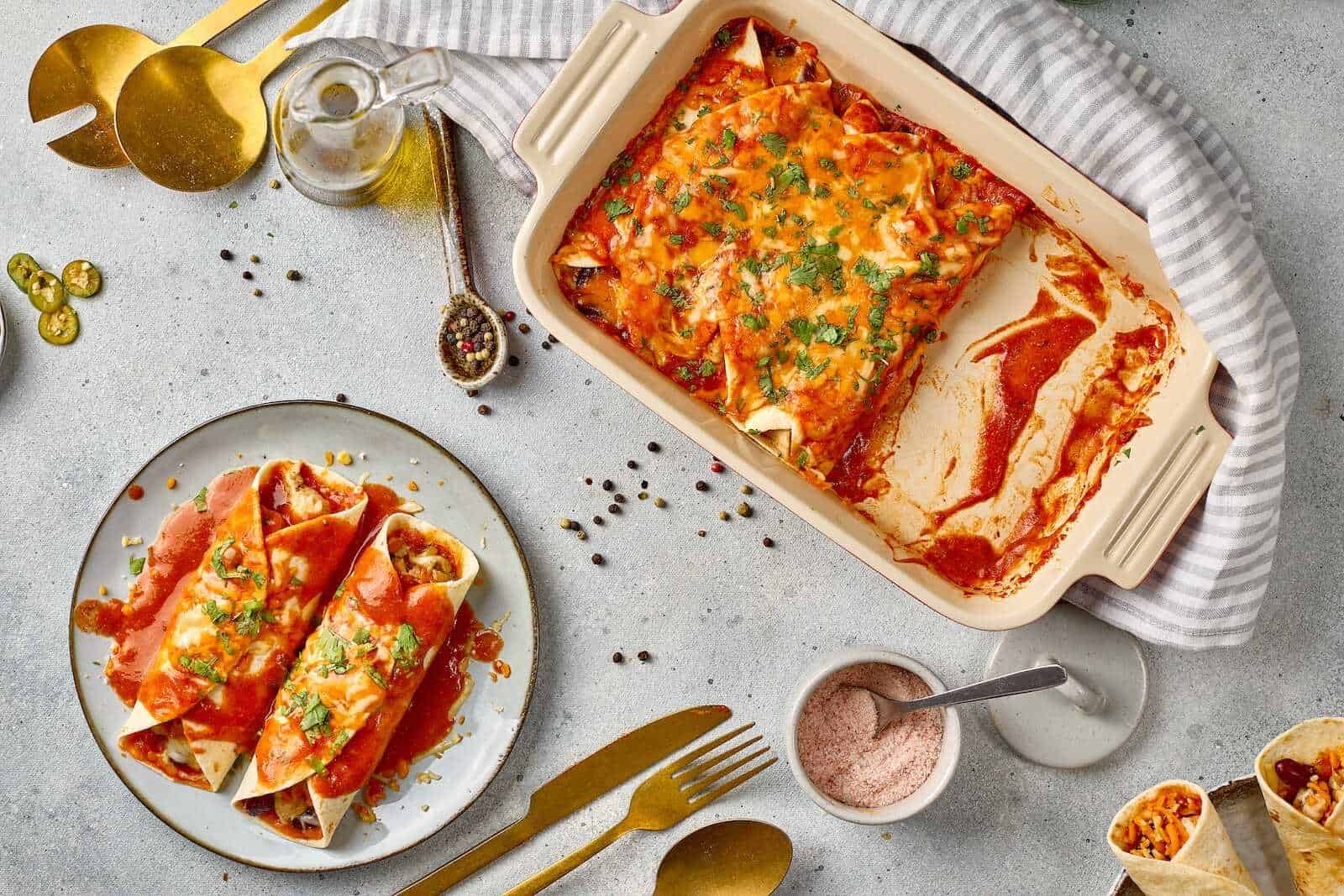 Delicious baked chicken enchiladas with melted cheese and fresh herbs on a baking dish.