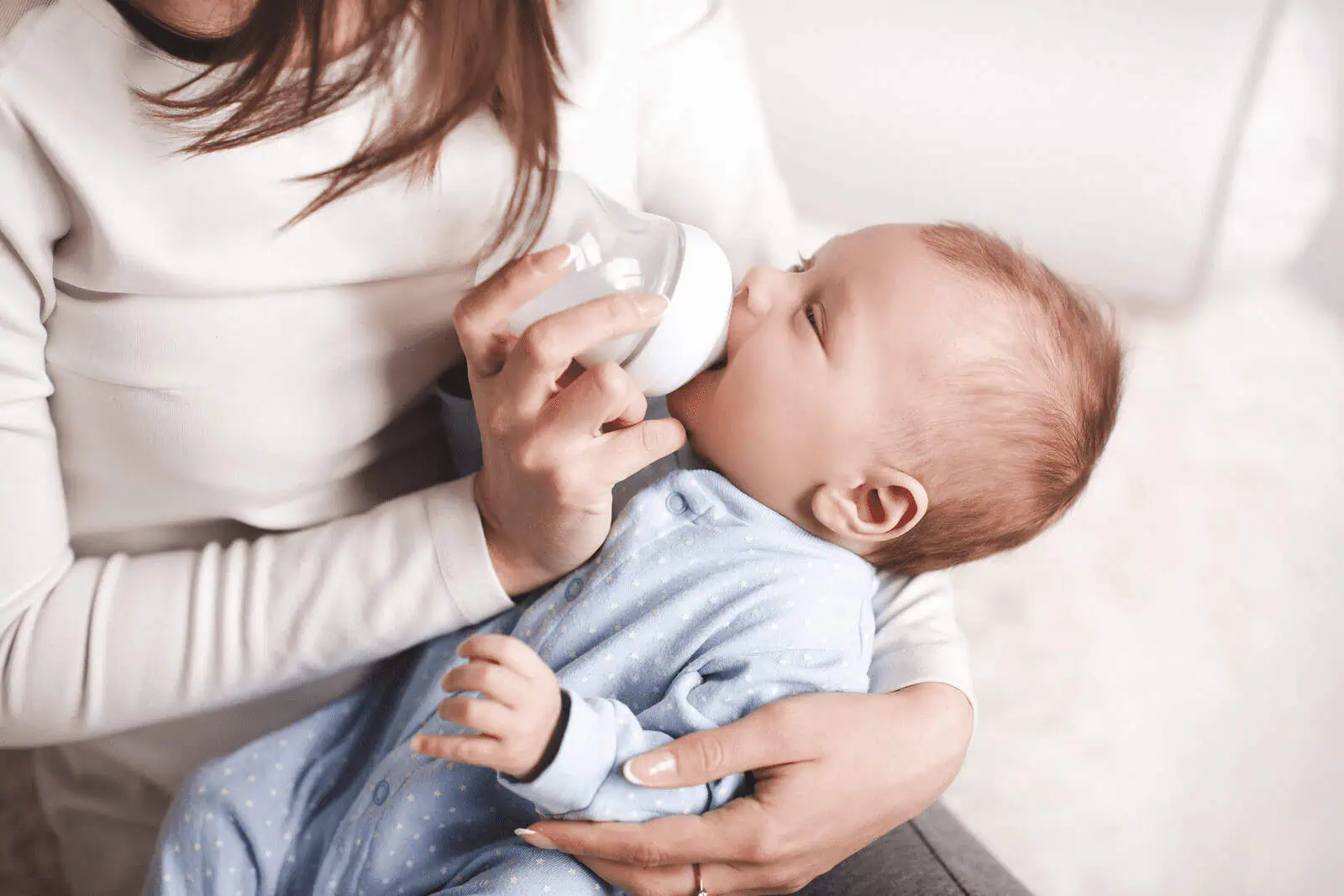 Mother feeding baby with glass bottle, parenting concept.