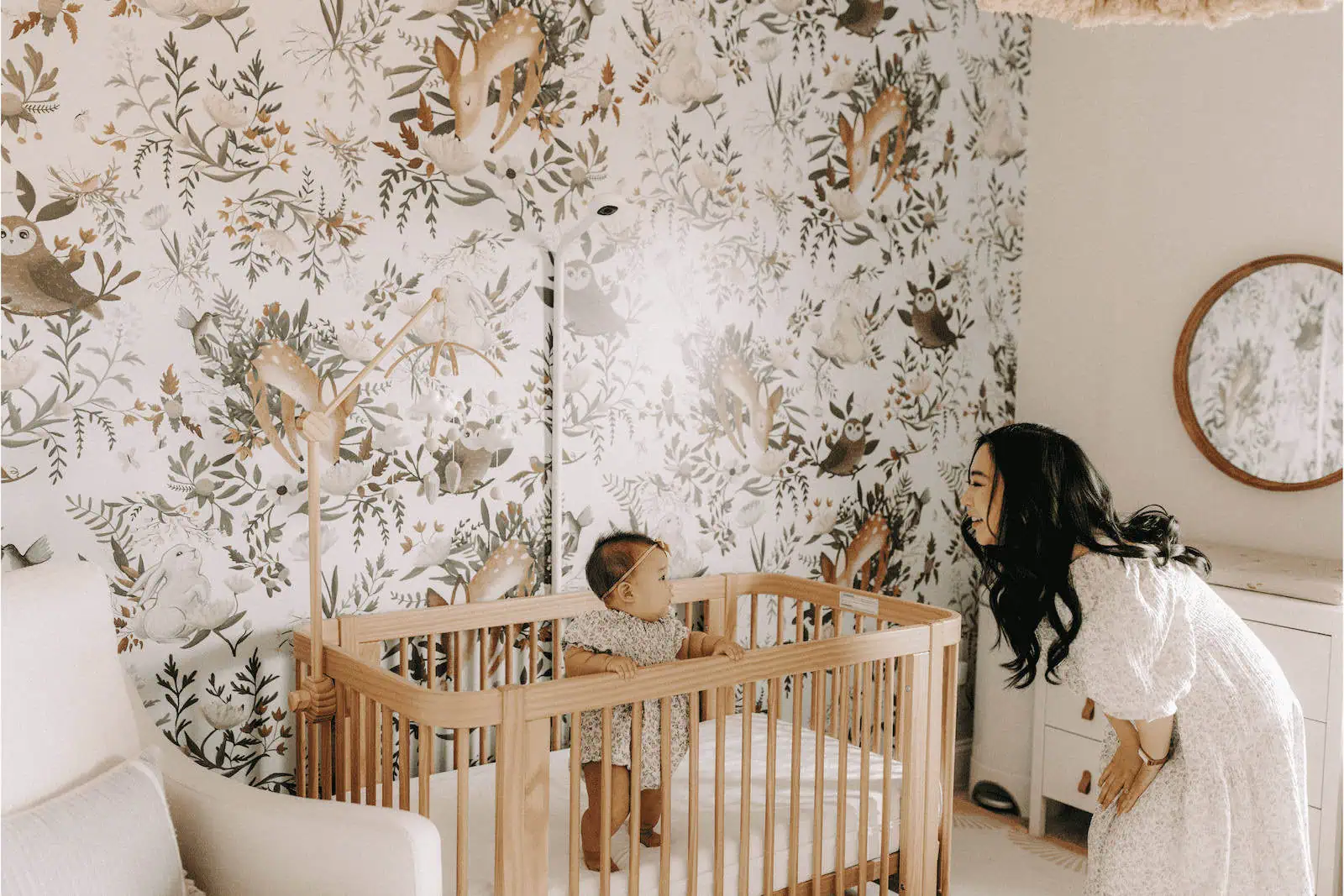 Beautiful mother and baby in nursery with woodland animal decor, fostering a loving surrogacy environment.