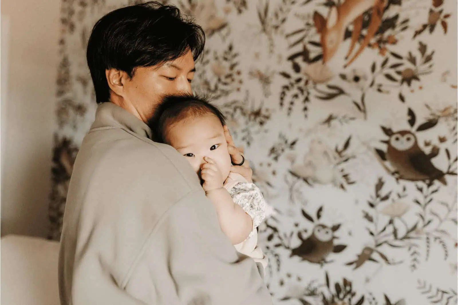 Adorable father holding baby girl, warm family bonding, surrogate family love, cozy home environment.