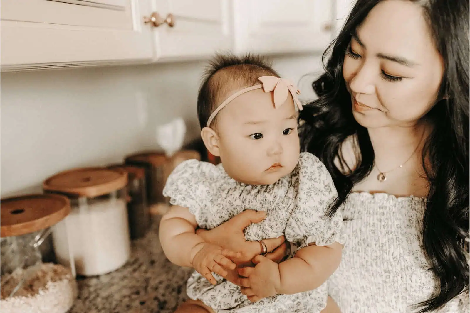 Adorable Asian baby girl with mother in cozy home setting, celebrating surrogacy and family bond.