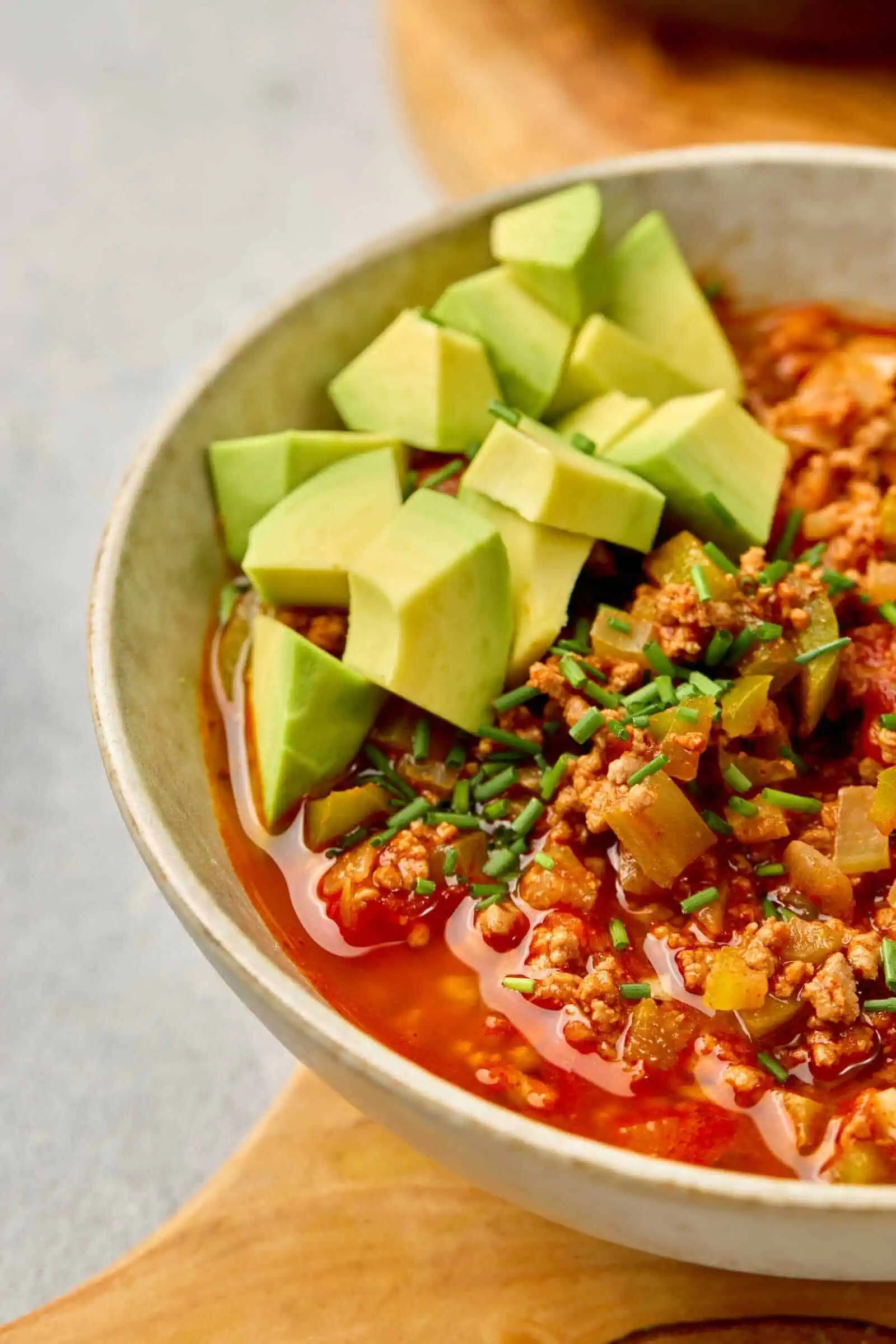 Fresh avocado and ground meat chili in a bowl, vibrant and healthy comfort food.
