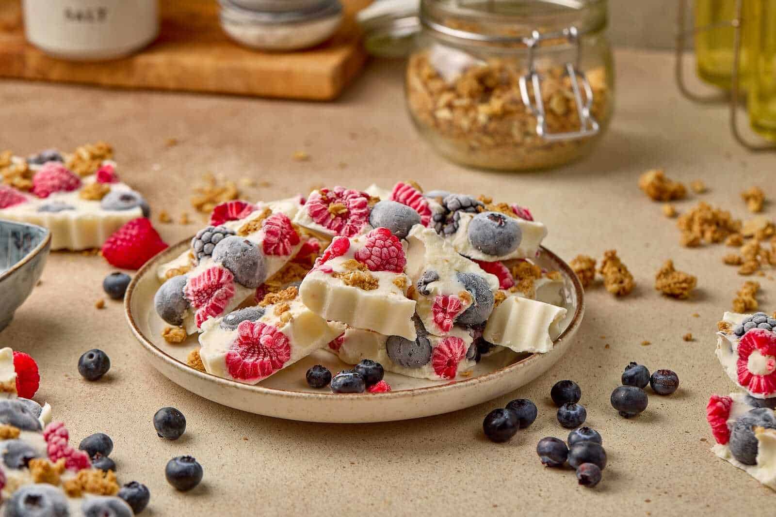 Healthy frozen yogurt bark topped with blueberries, raspberries, and granola for a nutritious treat.