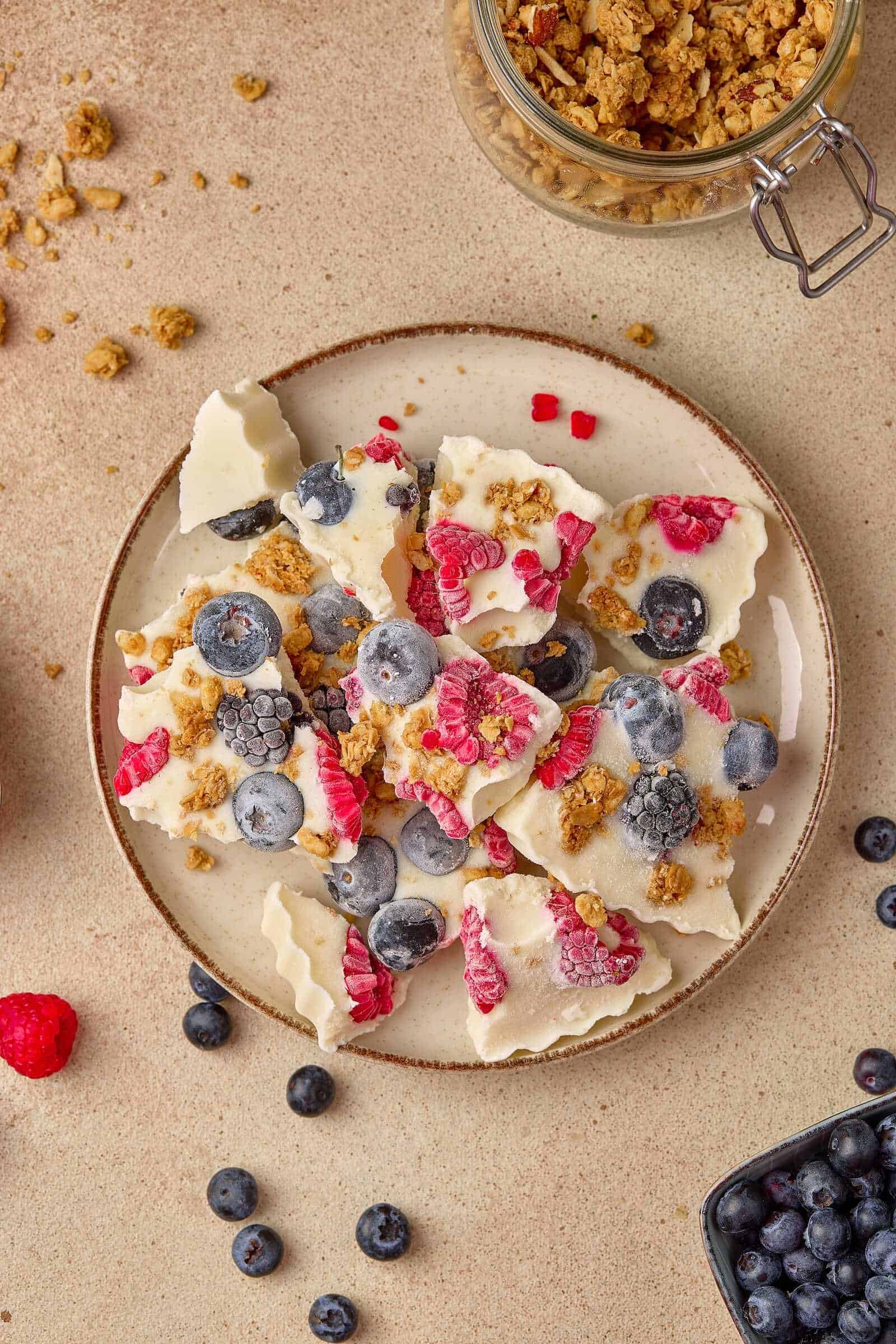 Delicious homemade white chocolate bark topped with fresh blueberries, raspberries, and crunchy granola, perfect for dessert or snack.