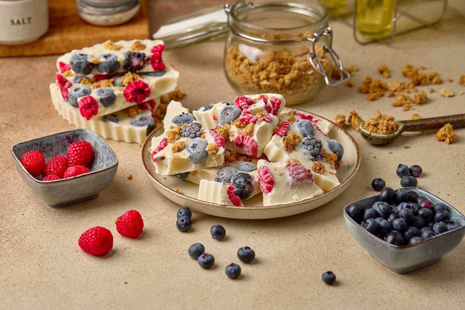 Delicious white chocolate bars topped with fresh berries, served with granola, perfect for dessert or snack.