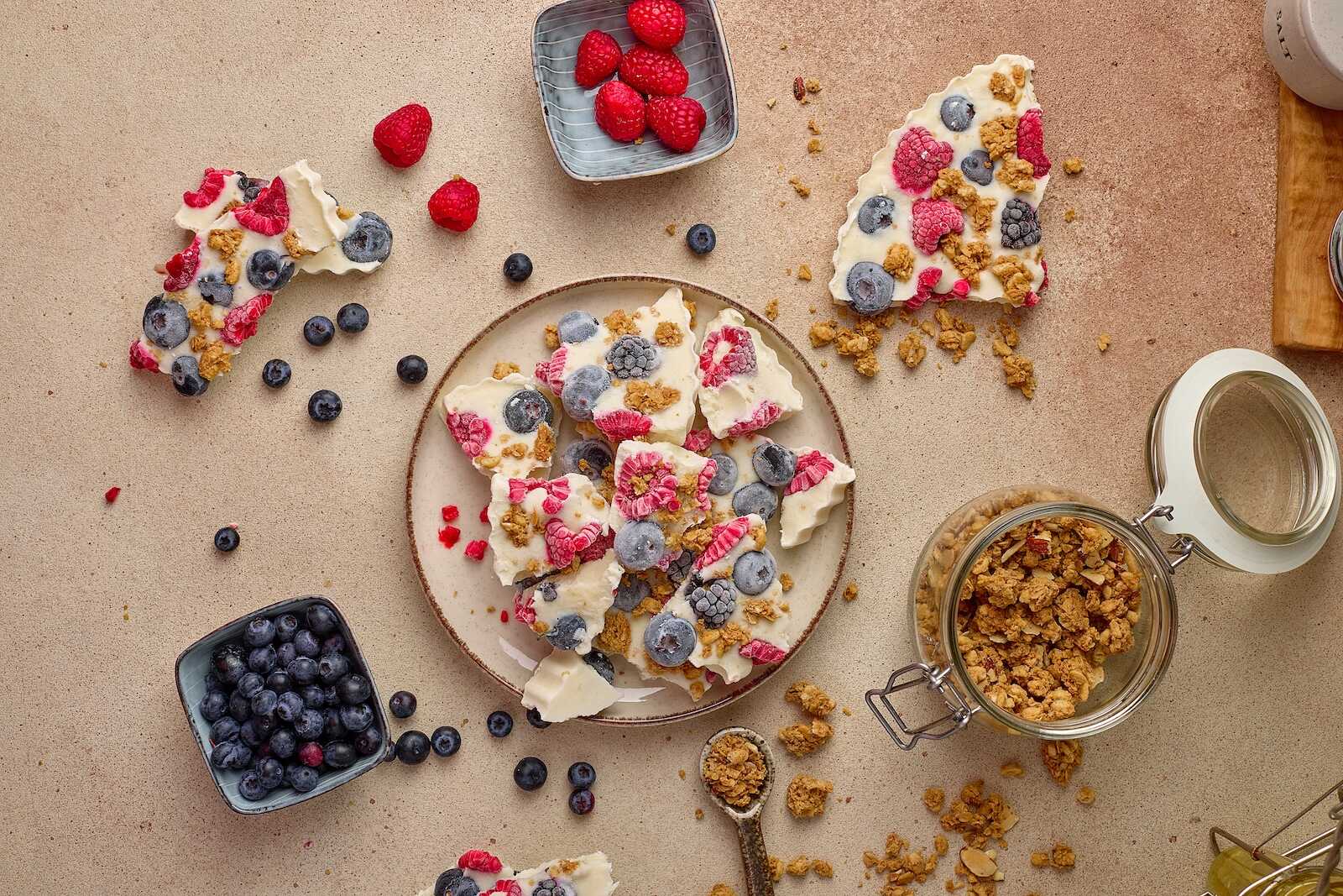 Delicious fresh berries with yogurt and crunchy granola on a neutral background, perfect for a healthy snack or breakfast.