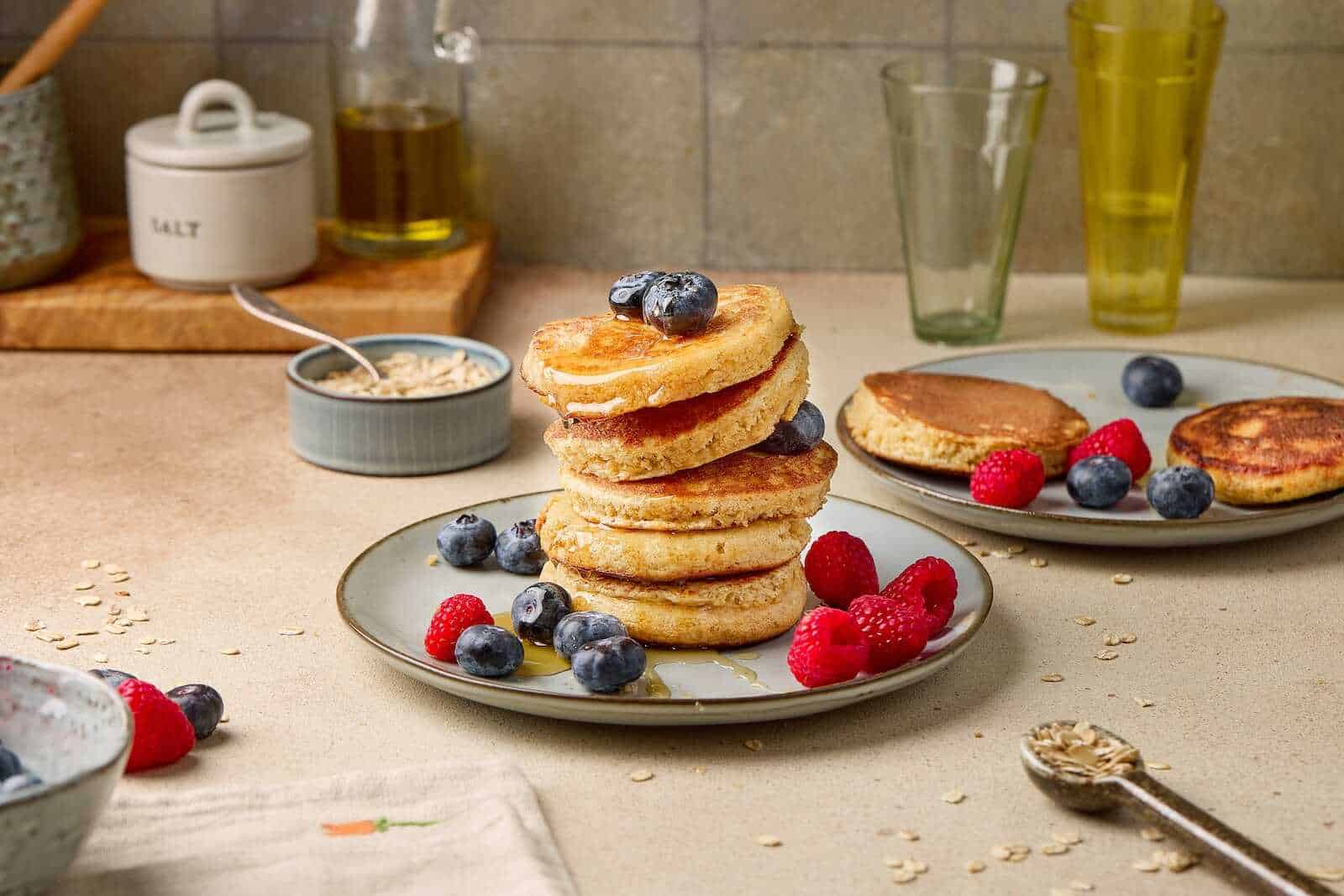 Delicious blueberry pancakes topped with fresh berries, served with syrup and side dishes on a cozy breakfast table.