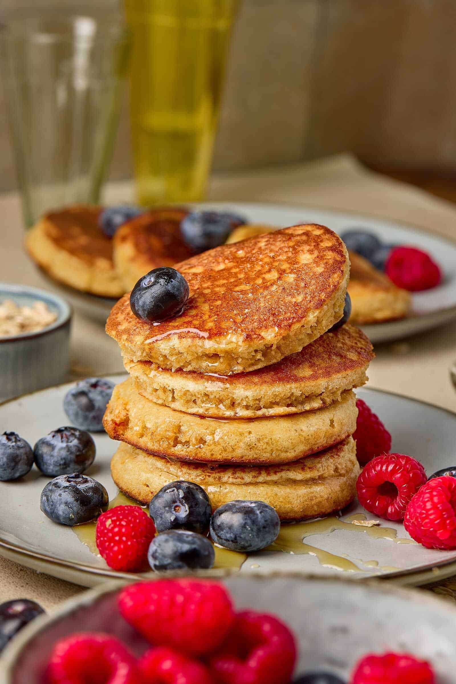 Delicious stack of pancakes with blueberries and raspberries, topped with syrup, ideal for surrogacy mama nutrition.