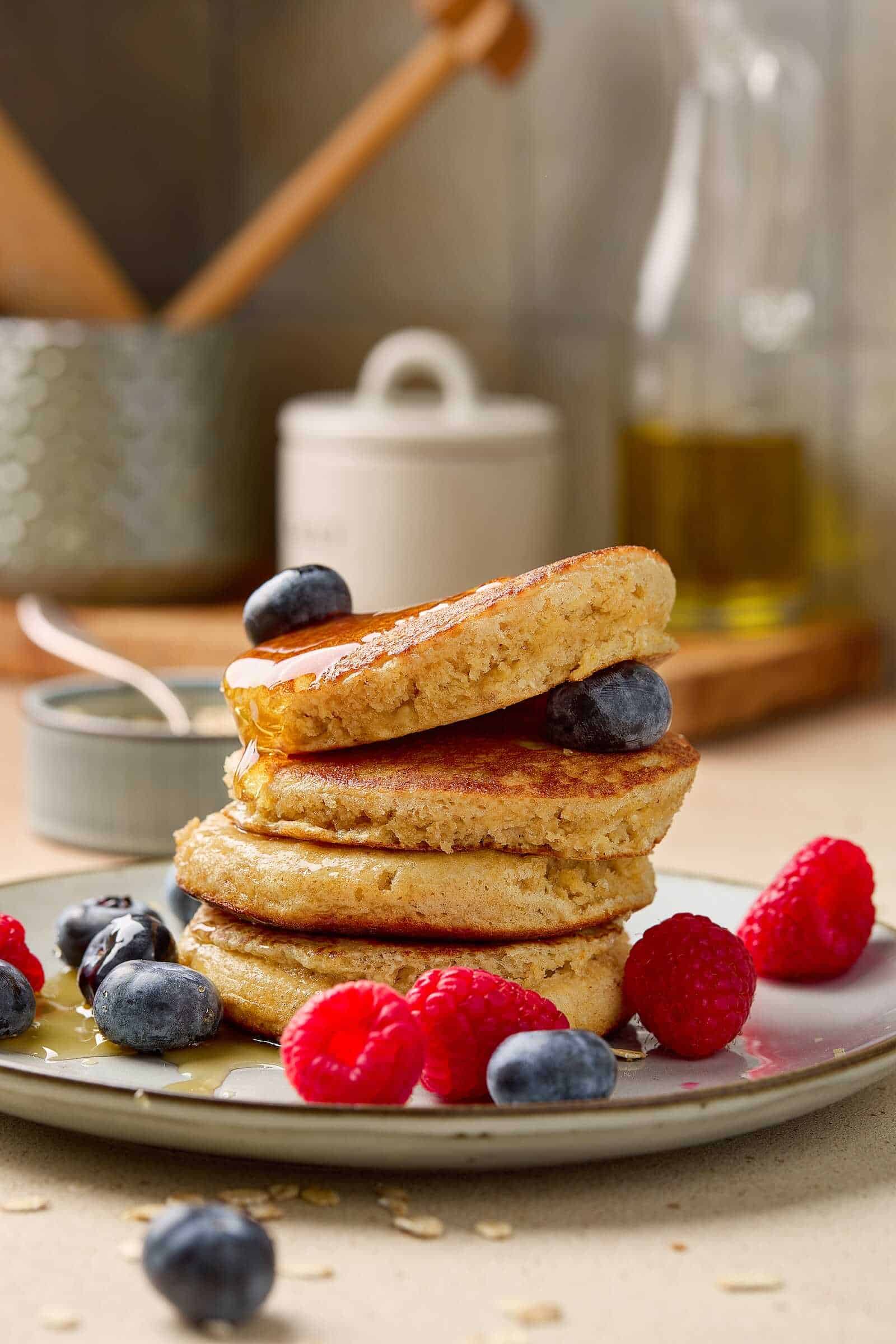 Delicious blueberry pancakes topped with fresh raspberries and syrup, ideal for breakfast or brunch.