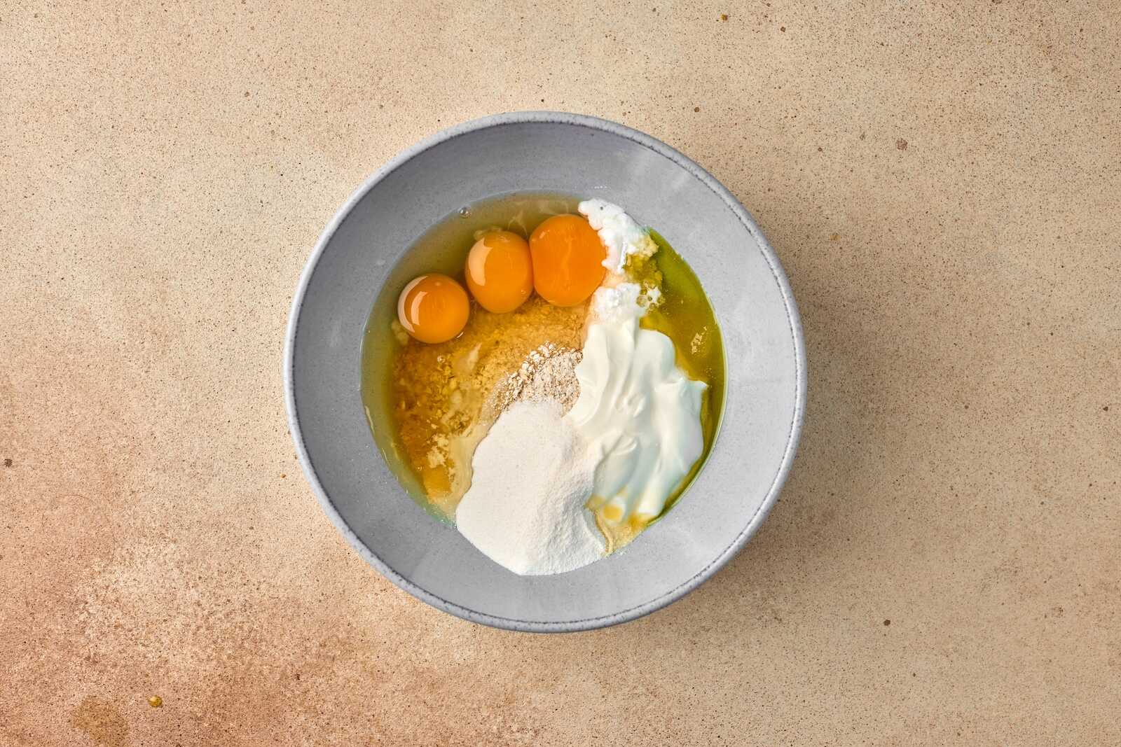 Delicious eggs with flour and yogurt in a gray bowl, ready for cooking or baking.