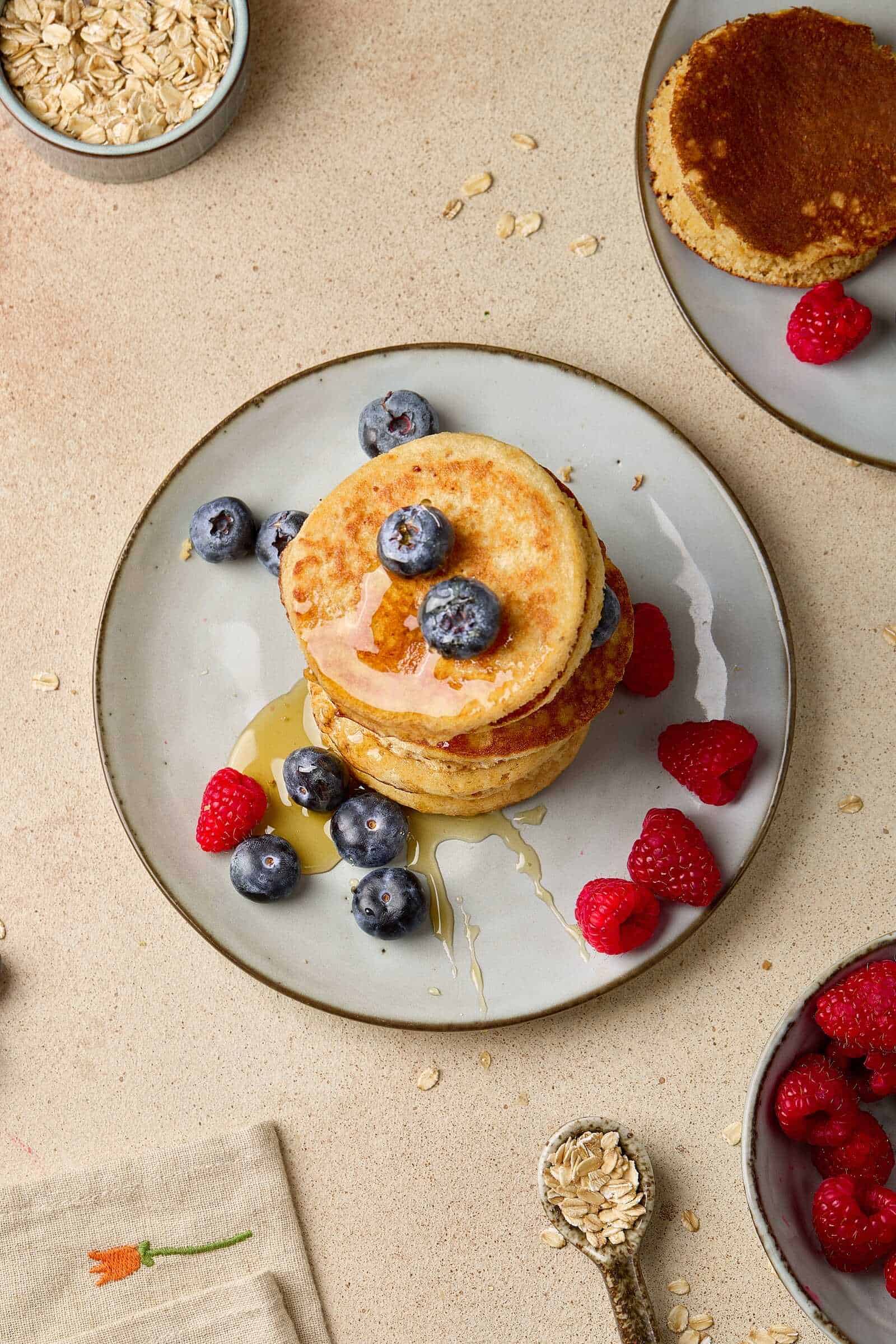 Delicious breakfast pancakes with fresh berries, syrup, and oats, ideal for morning meals.