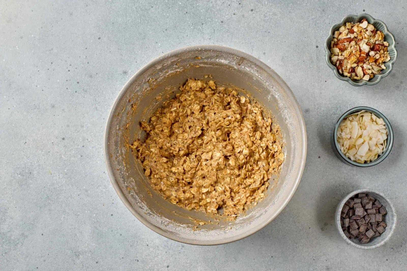 New cookie dough mixture with chocolate chips, chopped nuts, and butter in a bowl.