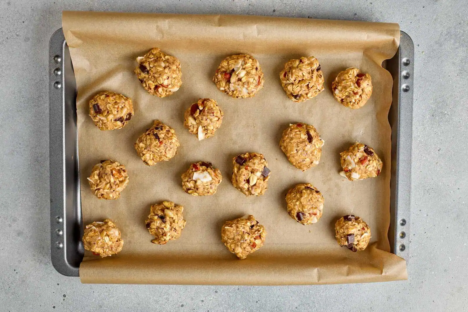 Delicious oatmeal cookies with nuts and dried fruits on baking sheet. Perfect snack for health-conscious families.